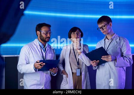 concetto futuristico, team multietnico di scienziati con appunti che lavorano nel centro dell'innovazione Foto Stock