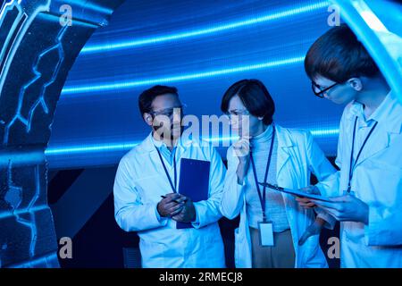 tecnologie futuristiche, discussione di scienziati multietnici in dispositivi sperimentali, centro scientifico Foto Stock