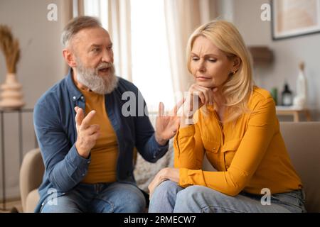 Un uomo maturo ed emotivo che gestiva gridando alla sua infelice moglie al chiuso Foto Stock