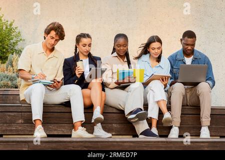 Studenti di gruppo multirazziale seduti sulla panchina, pronti per la lezione Foto Stock