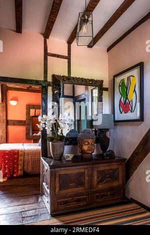 Orchidea e testa di Buddha su un petto d'epoca in una fattoria Tudor in legno, Surrey, Regno Unito Foto Stock