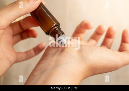 mani di donna che testano un rotolo con olio essenziale , applicando liquido al polso, messa a fuoco morbida primo piano Foto Stock