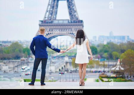 Coppia felice vicino alla Torre Eiffel. Turisti che si godono le loro vacanze in Francia. Un appuntamento romantico o un viaggio di coppia Foto Stock
