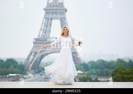 Bellissima giovane sposa in abito bianco vicino alla Torre Eiffel a Parigi il giorno del suo matrimonio Foto Stock