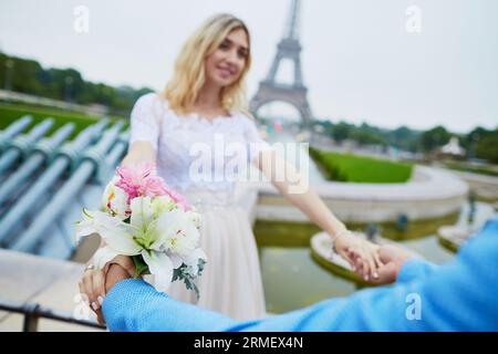 Coppia appena sposata a Parigi, in Francia. Bellissime giovani sposi e sposi vicino alla Torre Eiffel, ballando, girando o muovendosi insieme. Matrimonio romantico in Foto Stock