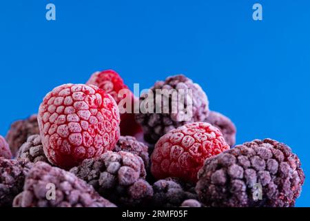 Micro primo piano dei lamponi congelati con spazio per la copia su sfondo blu Foto Stock