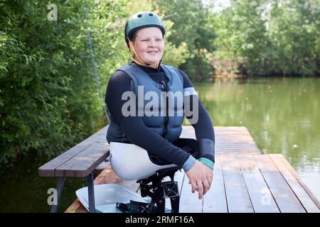 Ritratto di un giovane sorridente con disabilità che utilizza attrezzature sportive adattive e casco mentre si gode le attività all'aperto, spazio fotocopie Foto Stock