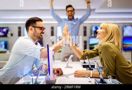 Il consulente di vendita consiglia le persone che scelgono nuovi dispositivi digitali nei punti vendita. Consulenza professionale Foto Stock