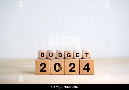 Concetto del piano di bilancio per l'anno 2024. allocazione. Testo "BUDGET 2024" con icona di calcolo finanziario su blocchi cubi in legno su sfondo bianco con copia spac Foto Stock