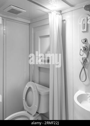 Interno del bagno stretto e pulito con WC a filo con divisorio per tende vicino alla doccia sul lavandino della vasca, stile verticale. Design moderno in polvere prefabbricata Foto Stock