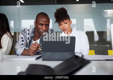Colleghi seduti a una riunione di lavoro e che utilizzano un tablet digitale Foto Stock