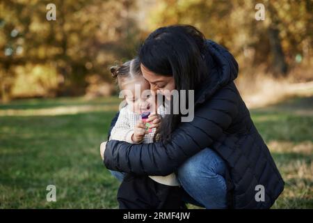 Madre felice che abbraccia la figlia al parco Foto Stock