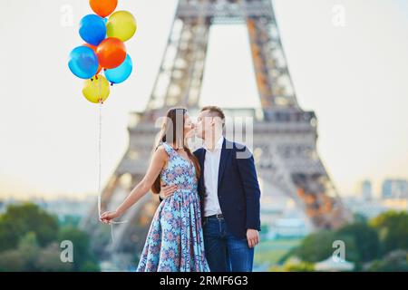 Coppia amorevole con un sacco di palloncini colorati che si baciano vicino alla Torre Eiffel a Parigi, in Francia Foto Stock