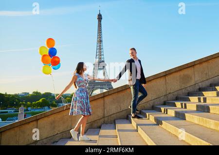 Coppia romantica con palloncini colorati vicino alla Torre Eiffel a Parigi, Francia, salendo le scale Foto Stock