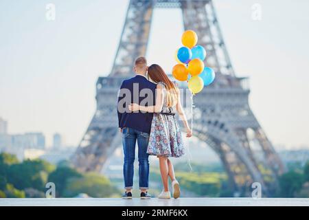 Coppia amorevole con un mucchio di palloncini colorati che guardano la Torre Eiffel a Parigi, in Francia Foto Stock