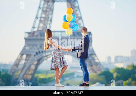 Coppia amorevole con un mucchio di palloncini colorati che guardano la Torre Eiffel a Parigi, in Francia Foto Stock