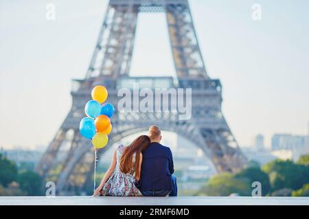 Coppia amorevole con un mucchio di palloncini colorati che guardano la Torre Eiffel a Parigi, in Francia Foto Stock