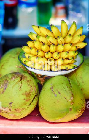 Banane fresche e noci di cocco su un mercato balinese Foto Stock