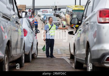 (230828) -- YIBIN, 28 agosto 2023 (Xinhua) -- questa foto scattata il 1° luglio 2023 mostra Zhong Helin, un marinaio del traghetto attraverso il fiume che collega la città di Nixi e la città di Juexi nel distretto di Xuzhou di Yibin nella provincia del Sichuan nella Cina sud-occidentale, dirige i veicoli sul ponte. Il servizio di traghetto attraverso il fiume che collega la città di Nixi e la città di Juexi nel distretto di Xuzhou di Yibin è iniziato nel maggio 1992. Questo servizio di traghetto e' stato uno dei piu' importanti metodi di trasporto per le persone locali che vivono nelle vicinanze su entrambi i lati del fiume Minjiang. Dato che il grande ponte di Nixi Minjiang si e' aperto al traffico qui su Mon Foto Stock