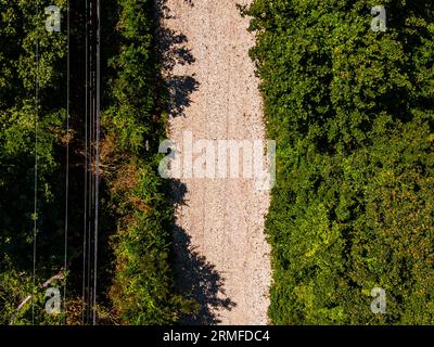 Una vista dall'alto verso il basso su una strada sterrata vicino alla spiaggia fiancheggiata da lussureggianti alberi verdi Foto Stock