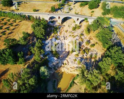 Vista aerea del ponte Giuliano (Pont Julien), ponte romano ad arco in pietra con cipressi circostanti, ulivi e vigneti in Provenza, a sud Foto Stock