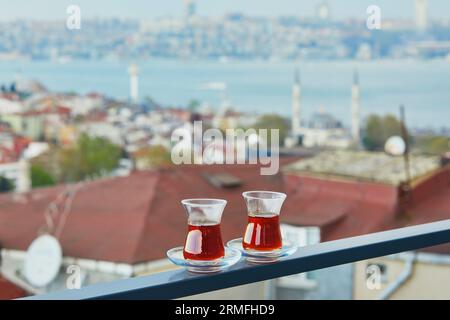 Due bicchieri turchi a forma di tulipano riempito di tè nero caldo con vista sui tetti del distretto di Uskudar sul lato asiatico di Istanbul, Turchia Foto Stock