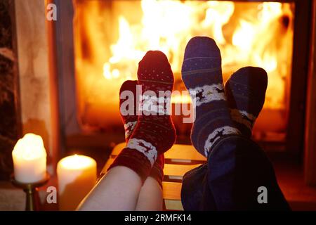 Uomo e donna in calze calde vicino al caminetto. Intima e romantica serata per due o festa di Natale Foto Stock