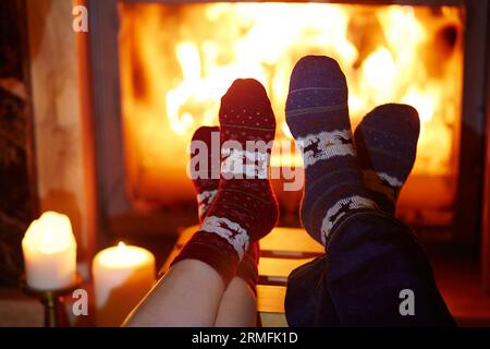 Uomo e donna in calze calde vicino al caminetto. Intima e romantica serata per due o festa di Natale Foto Stock