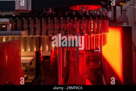 Jessen, Germania. 28 agosto 2023. Le preforme per bottiglie in PET passano attraverso una ruota riscaldante in produzione presso Roxane GmbH. La società francese Roxane ha rilanciato il sito a Jessen dopo 15 anni. 50 nuovi posti di lavoro sono stati creati nello stabilimento nel distretto di Wittenberg. Si prevede che gli impianti producano fino a 350 milioni di bottiglie d'acqua all'anno. Al centro di tutto ciò vi sono i nuovi impianti di produzione, che funzionano in modo completamente automatico dal riempimento all'etichettatura e all'imballaggio. Credito: Hendrik Schmidt/dpa/ZB/dpa/Alamy Live News Foto Stock