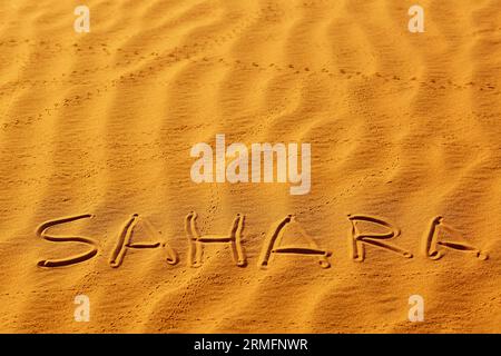 Parola Sahara scritta sulla sabbia nelle dune di sabbia del deserto del Sahara, Merzouga, Marocco Foto Stock