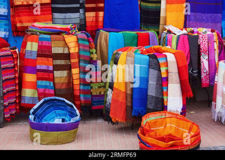 Tessuti e tappeti colorati in vendita in una strada a Medina di Essaouira, Marocco Foto Stock