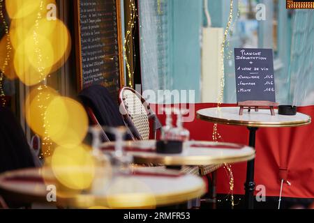 Accogliente caffetteria parigina all'aperto con luci gialle e menu a tavola, concentrati a bordo Foto Stock