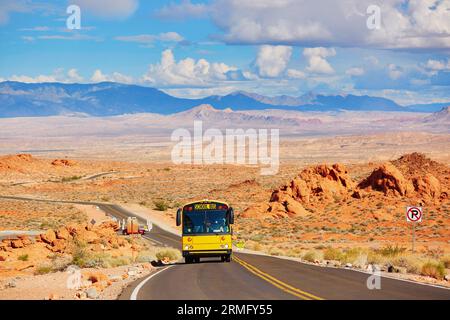 Paesaggio panoramico con strada tortuosa e scuolabus giallo durante la gita nel parco nazionale Valley of the Fire in Nevada, Stati Uniti Foto Stock