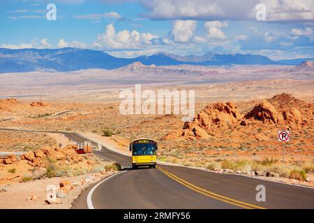 Paesaggio panoramico con strada tortuosa e scuolabus giallo durante la gita nel parco nazionale Valley of the Fire in Nevada, Stati Uniti Foto Stock