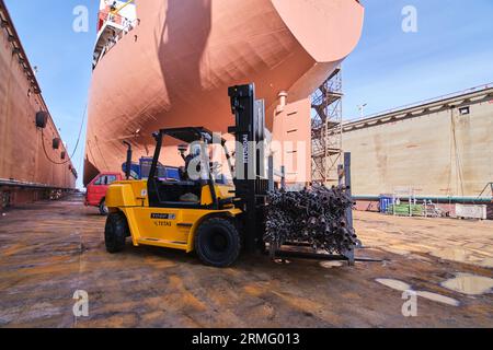 uomo che guida un carrello elevatore in un cantiere navale di un bacino di importazione e esportazione Foto Stock