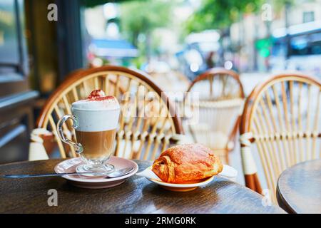Bicchiere di cappuccino e tradizionale pasticceria francese (pain au chocolat) in un caffè all'aperto a Parigi, in Francia Foto Stock