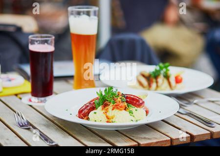 Salsicce tedesche tradizionali con purè di patate e birra nel ristorante all'aperto di Monaco, Germania Foto Stock