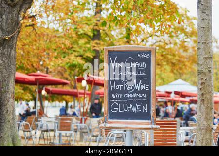 Menu con parole "vino caldo" in tre lingue nel caffè all'aperto parigino in autunno Foto Stock