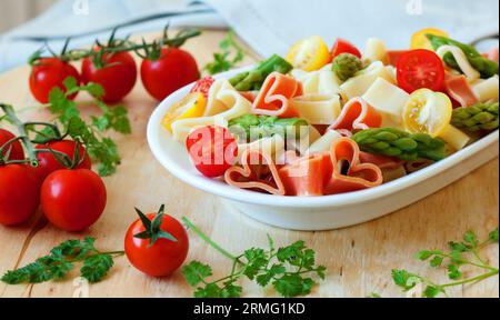 Cena romantica. Deliziosa pasta a forma di cuore con pomodori, asparagi ed erbe fresche Foto Stock