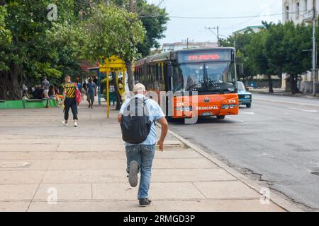 L'Avana, Cuba, 2023 anni, uomo anziano con zaino che corre per prendere un autobus Foto Stock