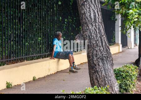 L'Avana, Cuba, 2023 anni, anziano cubano seduto in una recinzione accanto al marciapiede Foto Stock