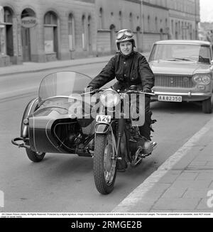 Negli anni '1960 Una donna ha visto vestirsi con il tipico costume da pilota motociclistico e casco alla sua moto con un sidecar per passeggero. Svezia 1967. Guidare una moto Foto Stock