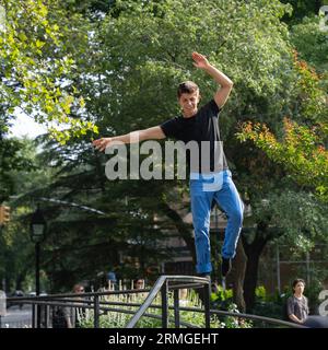 New York, USA - 21 luglio 2023: Un giovane che esegue acrobazie su una ringhiera in un parco di Manhattan, New York. Foto Stock