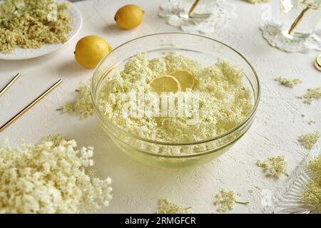 Fiori di sambuco macerando in una ciotola d'acqua - preparazione di sciroppo di erbe Foto Stock