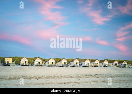 Piccole cabine su una fila di dune con un bel cielo serale durante il tramonto sulla spiaggia Foto Stock