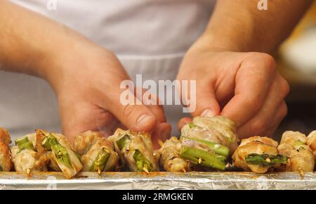 Gli chef dell'Ambasciata Giapponese stanno grigliando spiedini di pollo al Festival delle Ambasciate di Praga. Primo piano. Foto Stock