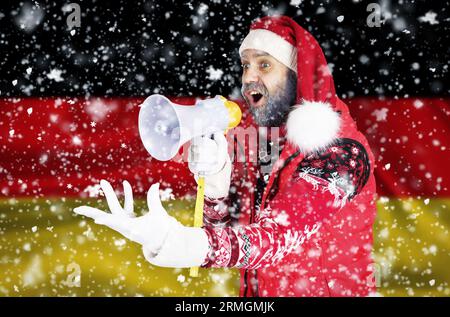 Babbo Natale grida in un corno e mostra un gesto aggressivo con la mano sullo sfondo della bandiera tedesca Foto Stock