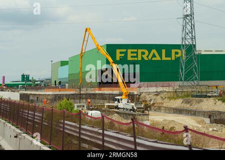 Brescia, Italia - 13 giugno 2023: Edificio di produzione della Feralpi che produce prodotti siderurgici. Vista di un edificio verde con un inscri giallo Foto Stock