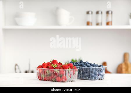 Contenitori in plastica con bacche mature sul tavolo in cucina Foto Stock