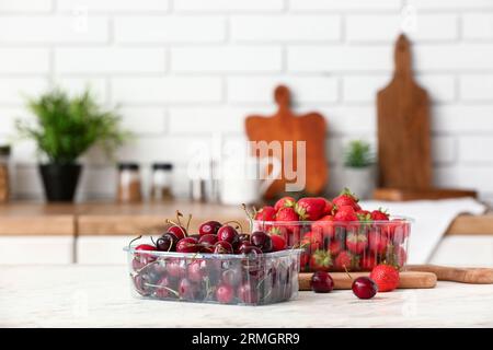 Contenitori in plastica con frutti di bosco freschi sul tavolo in cucina Foto Stock